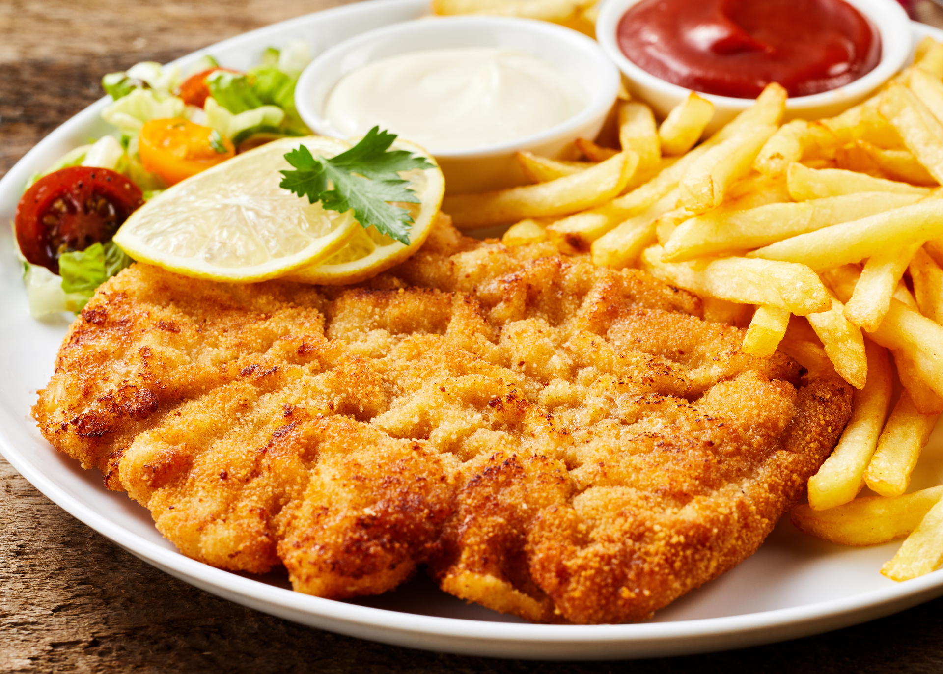 Goldbraun gebratenes Schnitzel mit Pommes und Salat